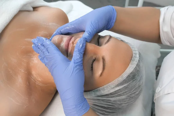 Cosmetologist médico está aplicando espuma de limpeza facial no rosto das mulheres, close-up. — Fotografia de Stock