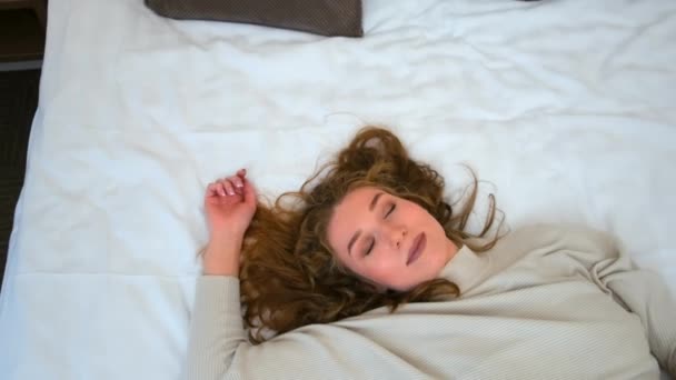 Retrato de jovem feliz cansado está deitado na cama no hotel após estrada dura. — Vídeo de Stock