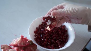 Kadınların elleri eldivenle masaya bir yakut kabuğu soyarken ve tabağa kabuk koyarken..