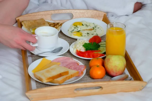 Paar frühstückt gemeinsam im Hotelbett, hölzerne Tablett-Nahaufnahme. — Stockfoto