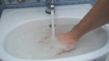 Adam lavabodaki tıkanmış ve su toplayan deliği temizlemeye çalışıyor..