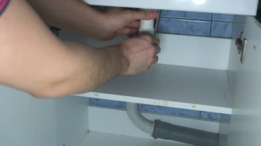 Adam lavabonun dibindeki boruyu söker, tıkanıklığı temizler..