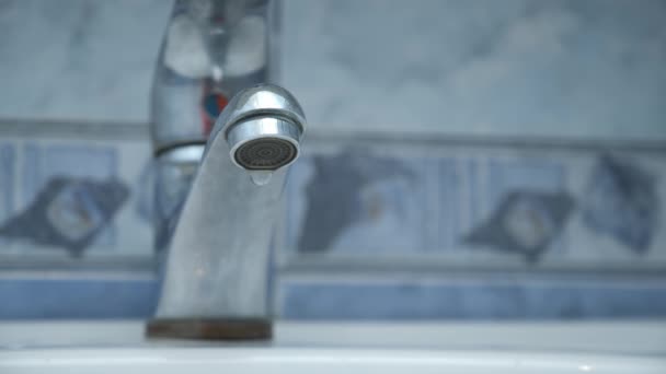 Víz csöpög a csapból a fehér mosogatóba a fürdőszobában, közelről. — Stock videók