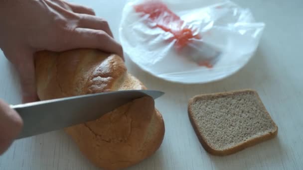 El hombre está haciendo sándwiches cortando pan de trigo blanco en la mesa, manos de cerca. — Vídeos de Stock