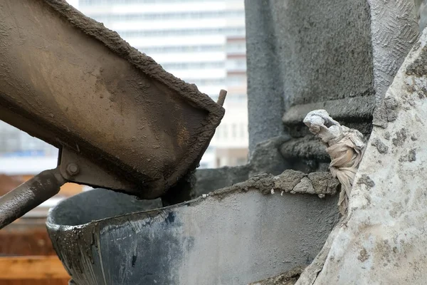 Concrete is poured from a concrete mixer into container on construction site. — Stock Photo, Image