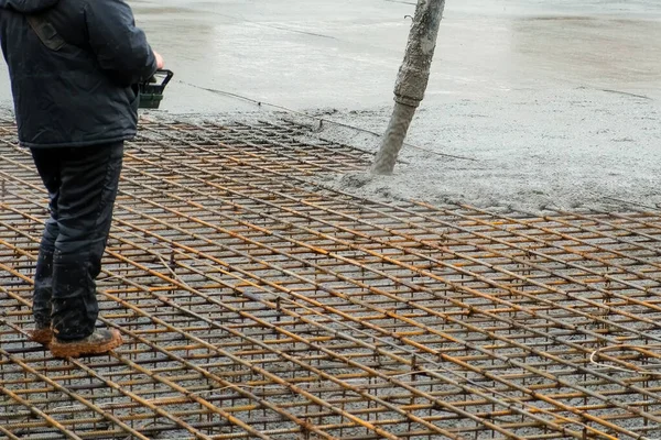 Muž nalévá základy mokrý těžký beton přes potrubí pomocí dálkového ovladače. — Stock fotografie