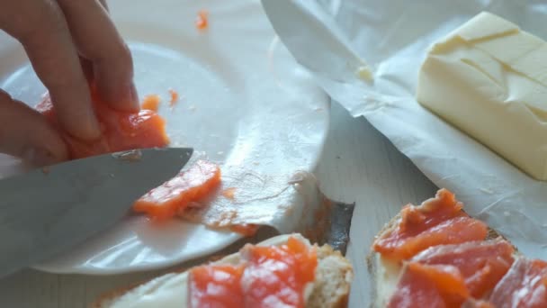 L'uomo sta tagliando il pesce salmone rosso e mettendo pezzi sul pane di grano facendo sandwich. — Video Stock