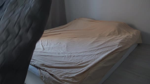 L'homme fait le lit dans la chambre à coucher écarte soigneusement plaid ou couverture sur le lit. — Video