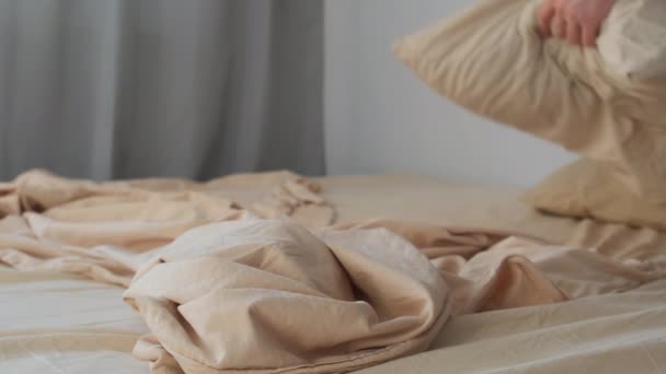 Mannen bäddar sin säng i sovrummet försiktigt sprider påslakan på sängen — Stockvideo