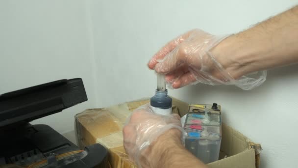 Man stopt zwarte inkt in een printer met behulp van een spuit, handen in handschoenen closeup. — Stockvideo