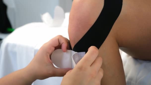 Physiothérapeute appliquant bande de kinésiologie à la jambe des femmes pour fixer l'articulation du genou. — Video