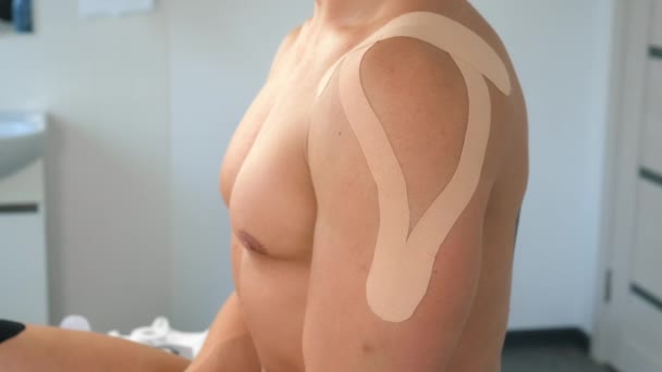 Kinesiology tapes on mans shoulder and hand for fixation of muscles, closeup. — Stock Video