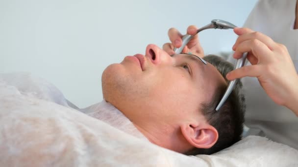 Chiropratico medico mette su fascia elettronica da emicrania sulla fronte uomo. — Video Stock