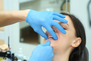 Ortodontist doktor kadın dişlerinin kapanmasını silikon eğitmenle kontrol ediyor..