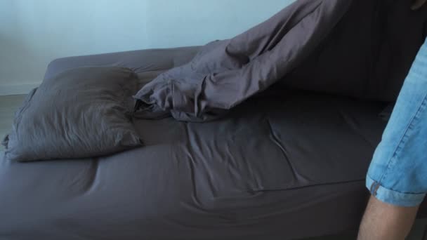 El hombre hace que la cama en el dormitorio se extiende cuidadosamente manta cubierta en la cama, primer plano. — Vídeo de stock