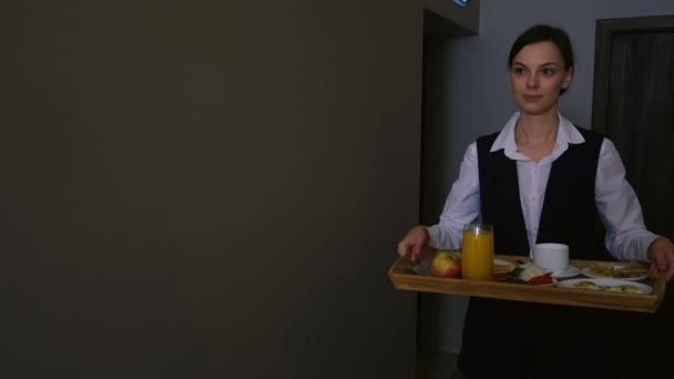 Женщина-работница отеля несет поднос для завтрака в комнату для гостей. — стоковое видео