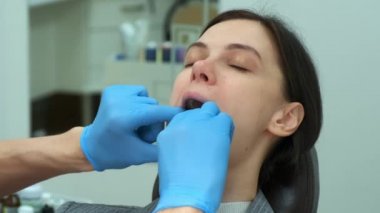 Kadın dişçi, doktor ağzına silikon diş eğitmeni sokuyor..