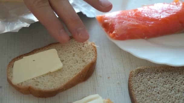 Hombre extiende mantequilla en un pedazo de pan de trigo haciendo sándwich para el desayuno. — Vídeo de stock