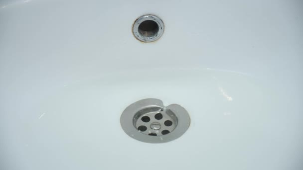 Water is draining in drain hole of the sink in bathroom, closeup view. — Stock Video