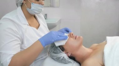 Kozmetik uzmanı ameliyattan önce peçete kullanarak kadınların yüzünü siliyor..