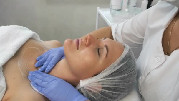 Beautician doctor is applying facial cleansing foam on womans face, closeup. — Stock Video