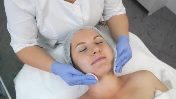 Kosmetolog otírá ženskou tvář pomocí vatových polštářků před olupováním. — Stock video