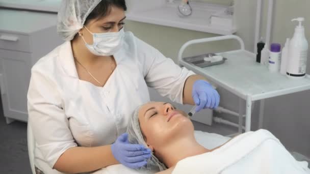 Kosmetolog nanáší žlutý peeling na ženský obličej pomocí injekční stříkačky. — Stock video