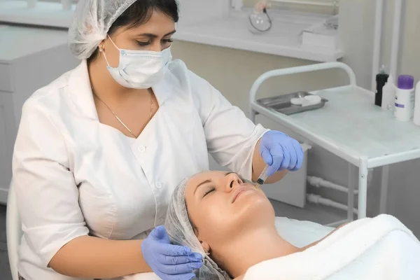 Cosmetologist está aplicando peeling amarelo no rosto das mulheres usando seringa. — Fotografia de Stock
