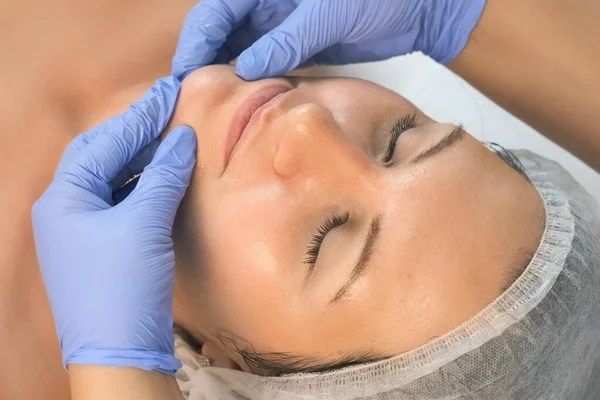 Cosmetologist médico fazendo massagem facial mioplásica para mulher na clínica de beleza. — Fotografia de Stock