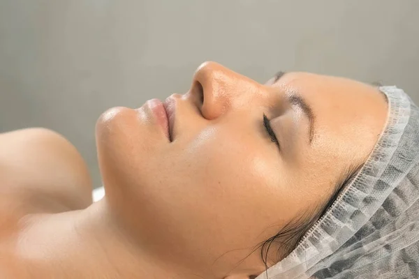Mulher na clínica de cosmetologia com peeling amarelo no rosto, vista lateral close-up. — Fotografia de Stock