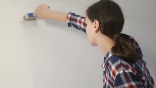 Жінка-художник малює стіну, використовуючи пензлик, роблячи ремонт в квартирі . — стокове відео