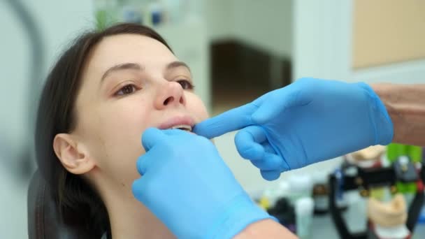 Médico ortodoncista comprueba el cierre de los dientes de la mujer con el entrenador de silicona. — Vídeo de stock