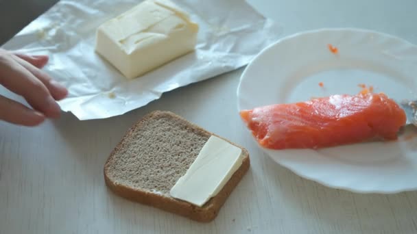 Homem espalha manteiga em um pedaço de pão de centeio fazendo sanduíche no café da manhã. — Vídeo de Stock