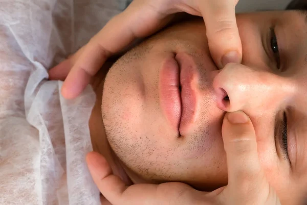 Manual therapist doctor is making facial massage for young man, top view. — Stock Photo, Image