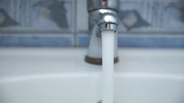 Klares Wasser strömt aus dem glänzenden Wasserhahn in die Spüle im Badezimmer, Nahaufnahme. — Stockvideo