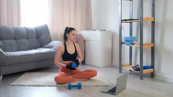 Giovane donna sta facendo esercizio tricipiti utilizzando manubri a casa formazione online. — Video Stock