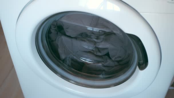 Washing machine with grey bedspread inside it starting to wash, laundry at home. — Video