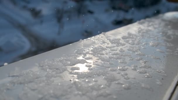 Wiosenne krople i topniejący śnieg na parapecie za oknem, zbliżenie. Wiosenne krople i topniejący śnieg na parapecie za oknem, zbliżenie. — Wideo stockowe