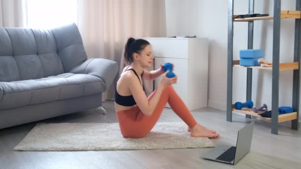 Woman is doing abs exercises crunches with dumbbell at home on online training. — Vídeo de Stock