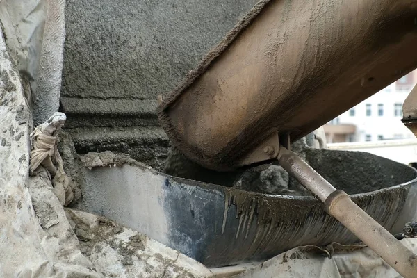 Concrete is poured from a concrete mixer into container on construction site. — Stock Photo, Image