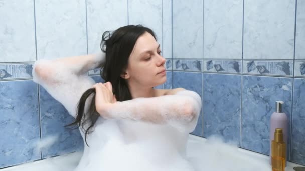 女性は自宅で泡とバスルームでリラックスした髪に油を適用しています. — ストック動画
