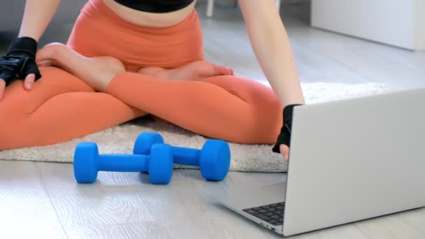 Mujer joven está haciendo ejercicio de tríceps usando pesas en el entrenamiento en casa en línea. — Vídeo de stock