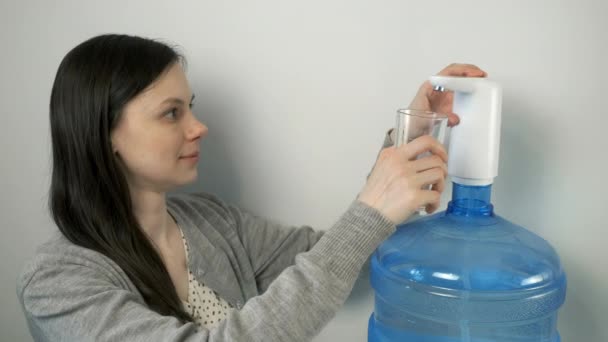 Mujer está vertiendo agua en el vidrio de un enfriador de agua automática y beber. — Vídeos de Stock