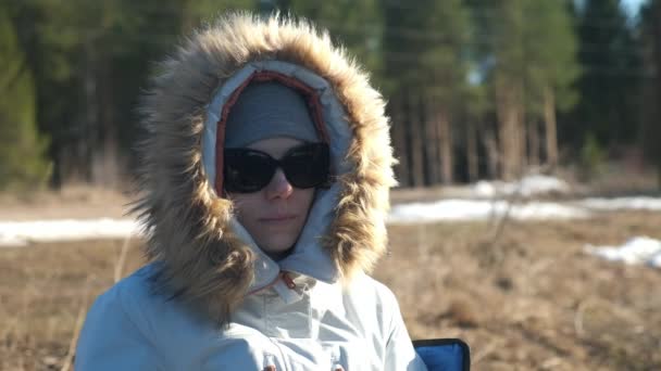 Retrato de mujer joven en sombrero, gafas de sol y capucha de piel de chaqueta en la naturaleza. — Vídeos de Stock