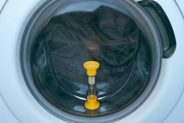 Çamaşır makinesinin camında kum saati, içinde yatak örtüsü, evde çamaşır.. — Stok fotoğraf