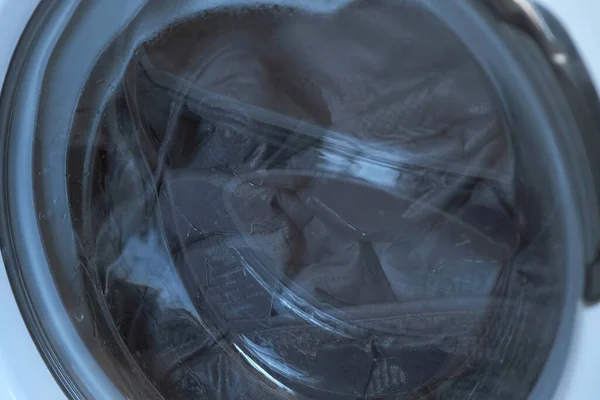 The washing machine rinses the laundry grey bedspread, closeup window. — Stock Photo, Image