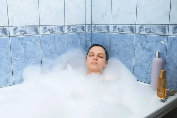 Mujer joven con los ojos cerrados relajante tumbado en el baño con espuma después de un día ocupado. — Foto de Stock