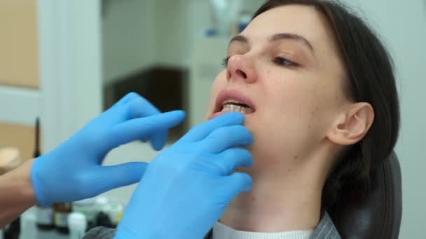 Orthodontiste médecin insère formateur de dents en silicone dans la bouche de la femme en dentisterie. — Video