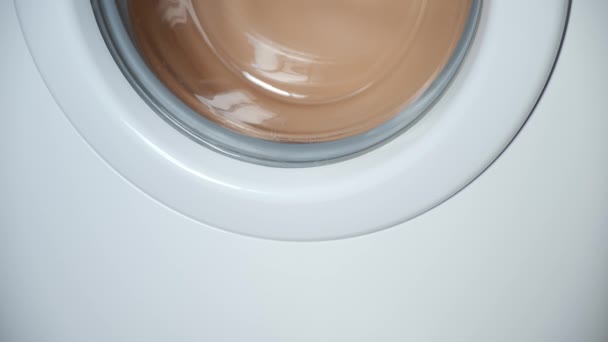 Wasmachine wikkelt de was beige beddengoed, close-up venster uitzicht. — Stockvideo