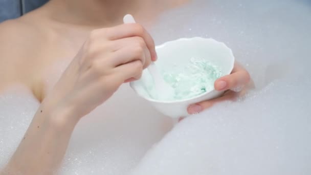 Young woman preparing mixing alginate mask lying in bathroom with foam at home. — Stock Video